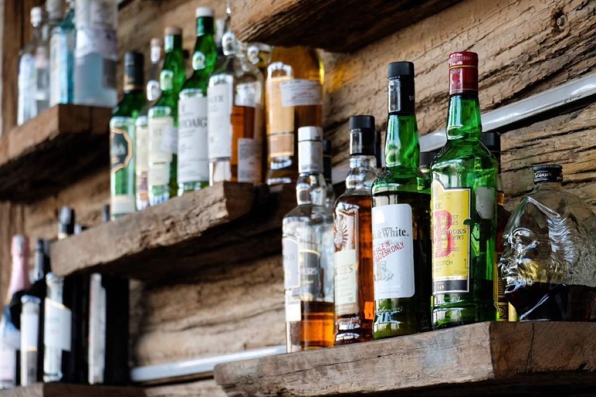 Rows of spirit bottles lined up on rustic wooden back-bar shelves
