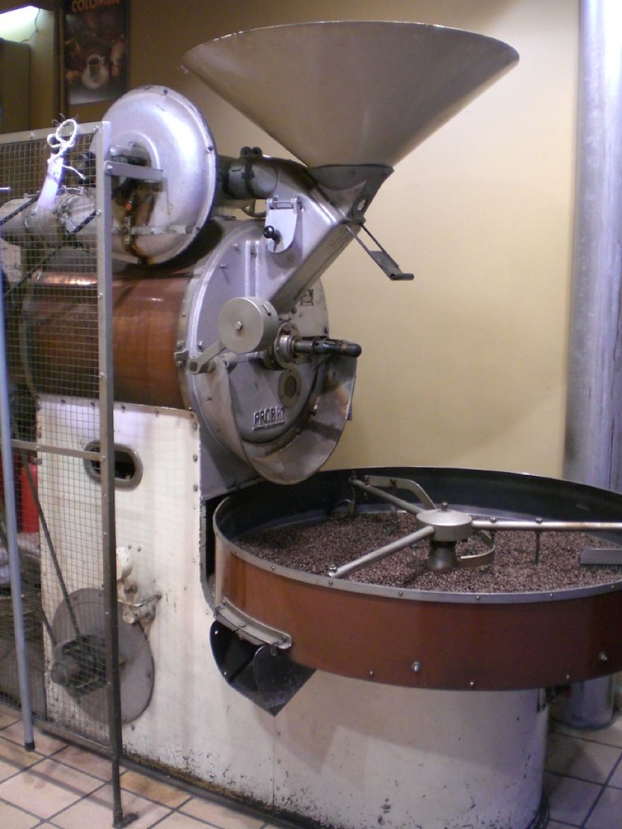 A vintage industrial coffee roasting machine with a hopper and beans visible in the cooling tray