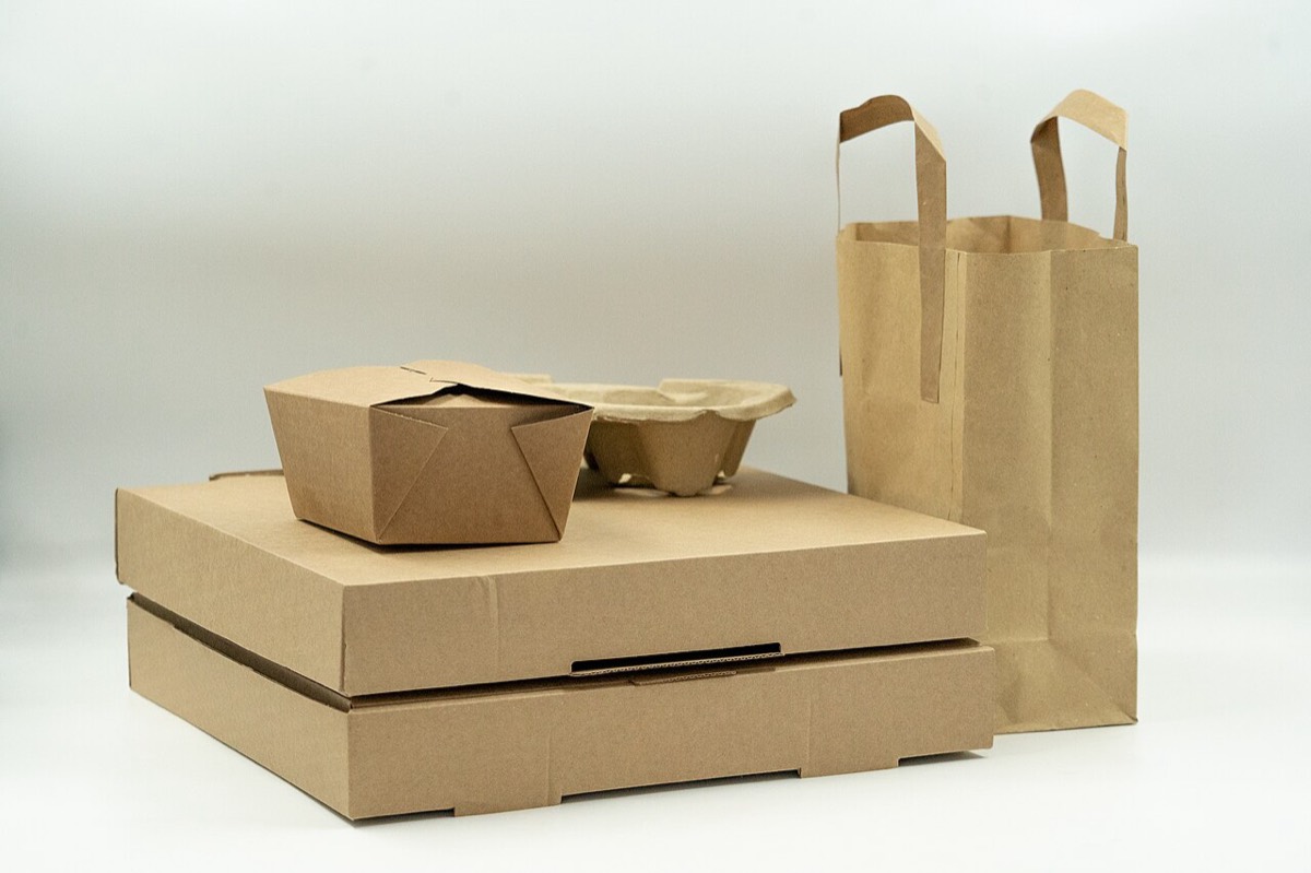 Kraft cardboard pizza boxes, a fold-top takeaway box, a moulded fibre tray, and a paper carrier bag arranged on a plain background