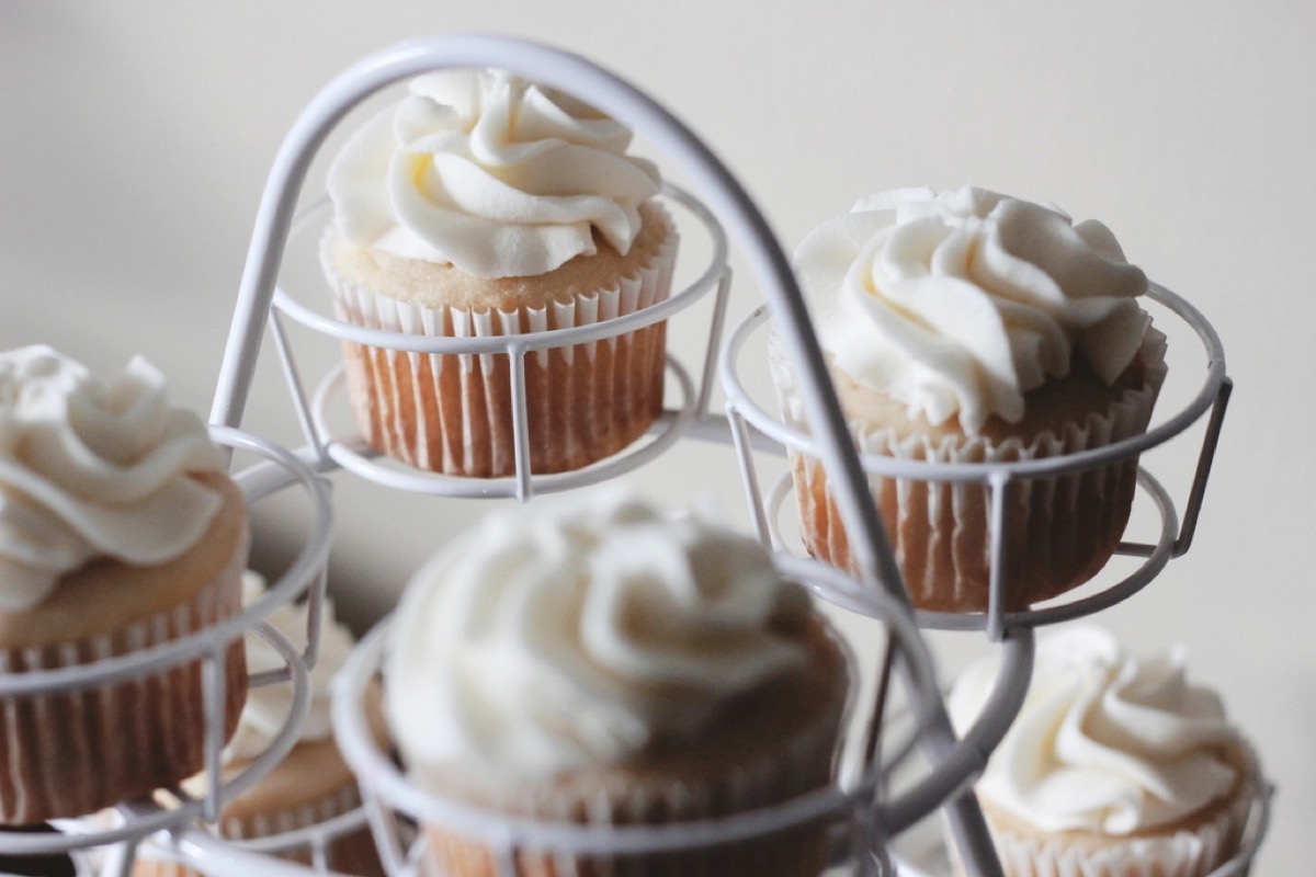 Vanilla cupcakes topped with swirled buttercream frosting on a white wire cupcake stand