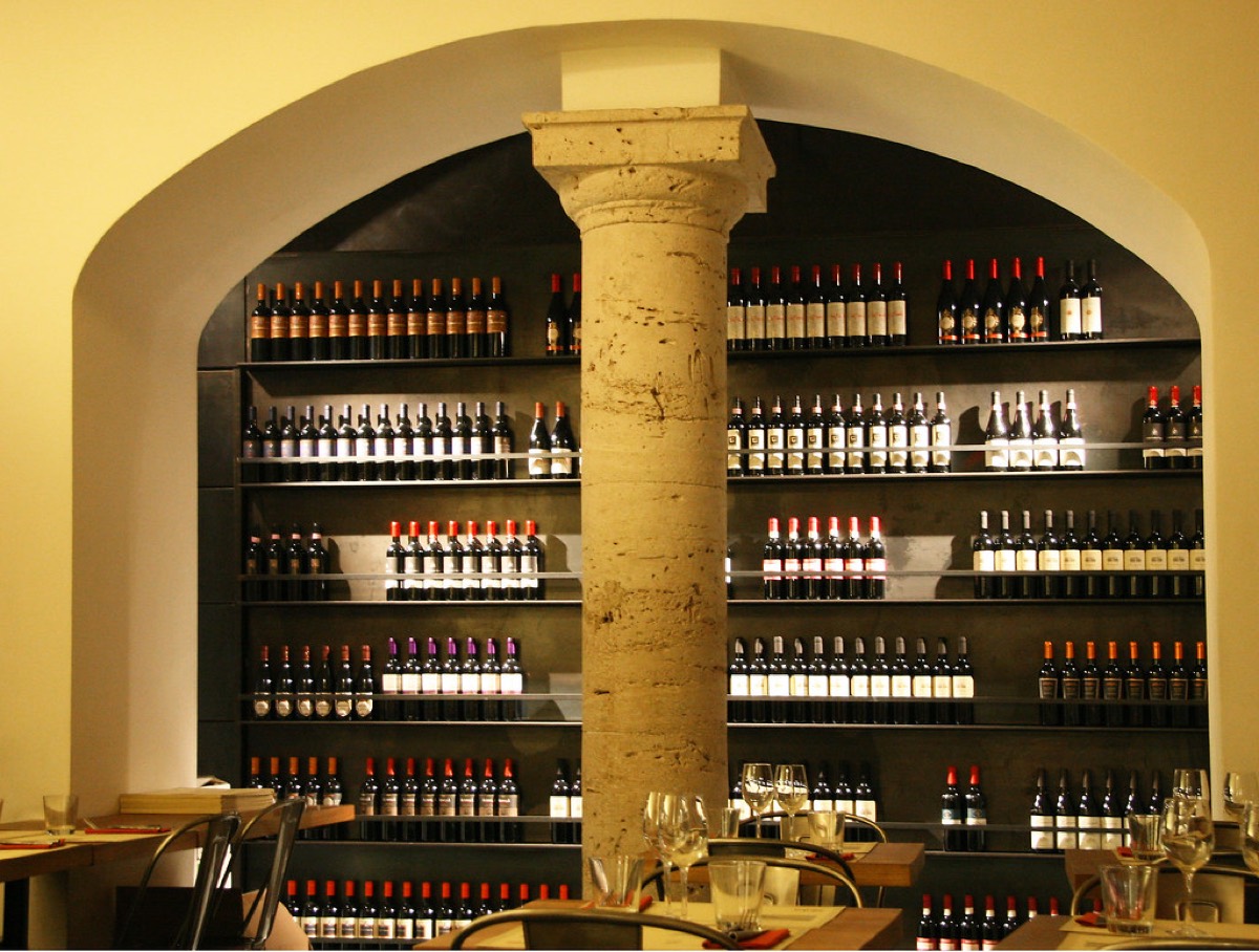 Arched wine bar interior with floor-to-ceiling wine bottle shelving and table settings